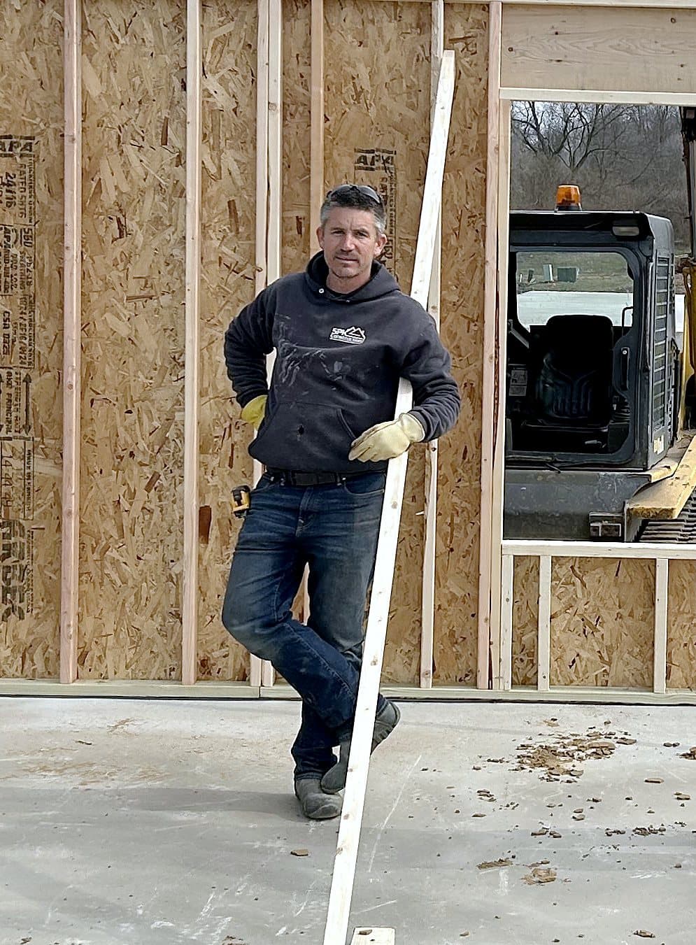 Shawn King on a job site, leaning on a stud inside a framed house