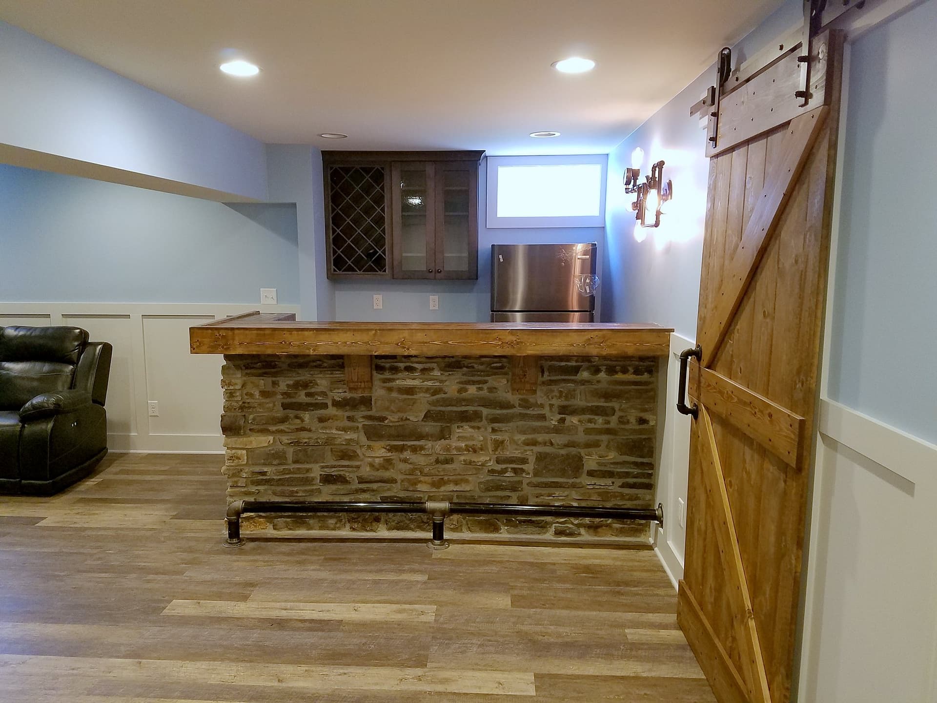 Basement bar with a stone front and a sliding barn door